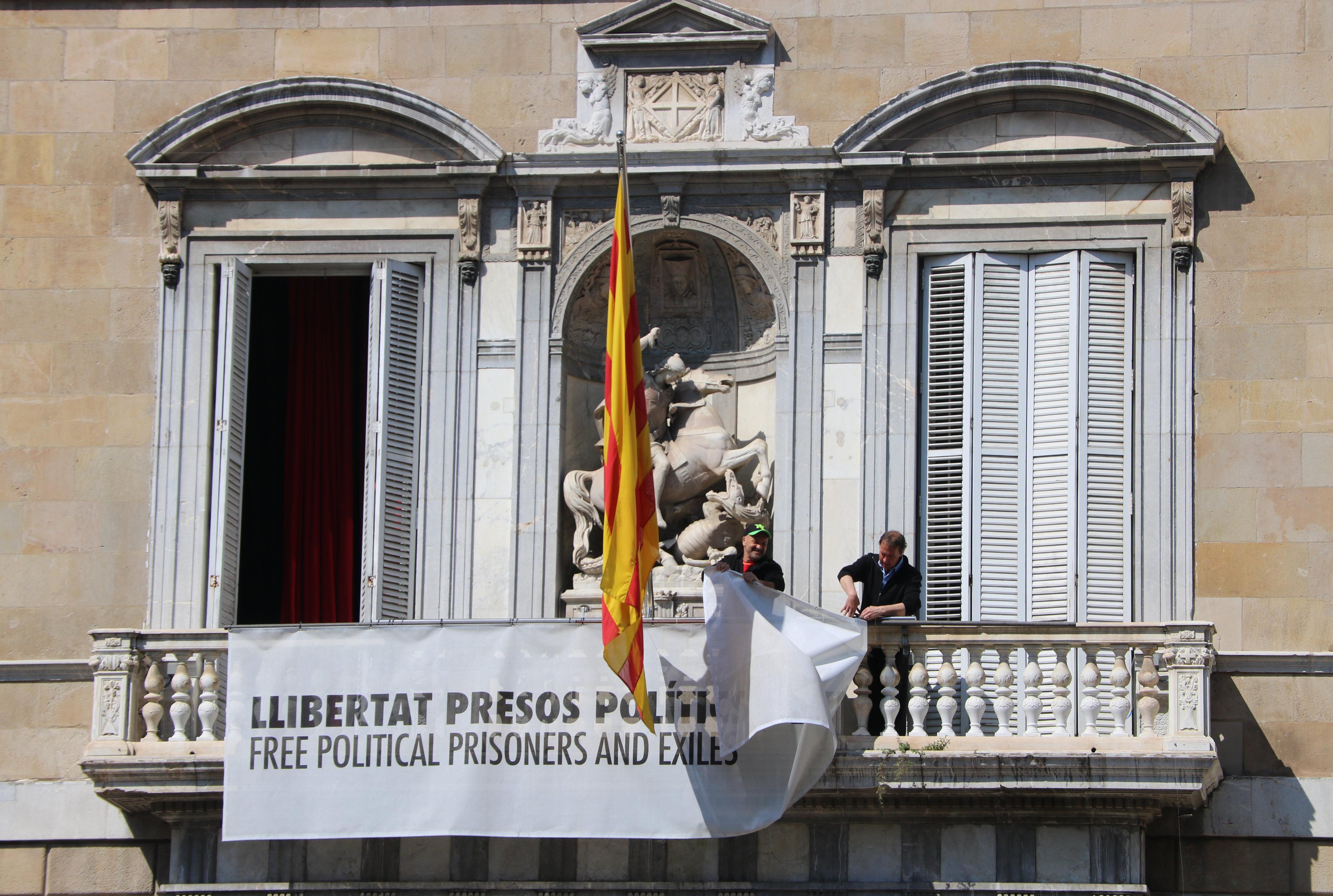 Workers take down a sign with a yellow ribbon on it on the Catalan government HQ's façade on March 22, 2019 (Miquel Codolar/ACN)